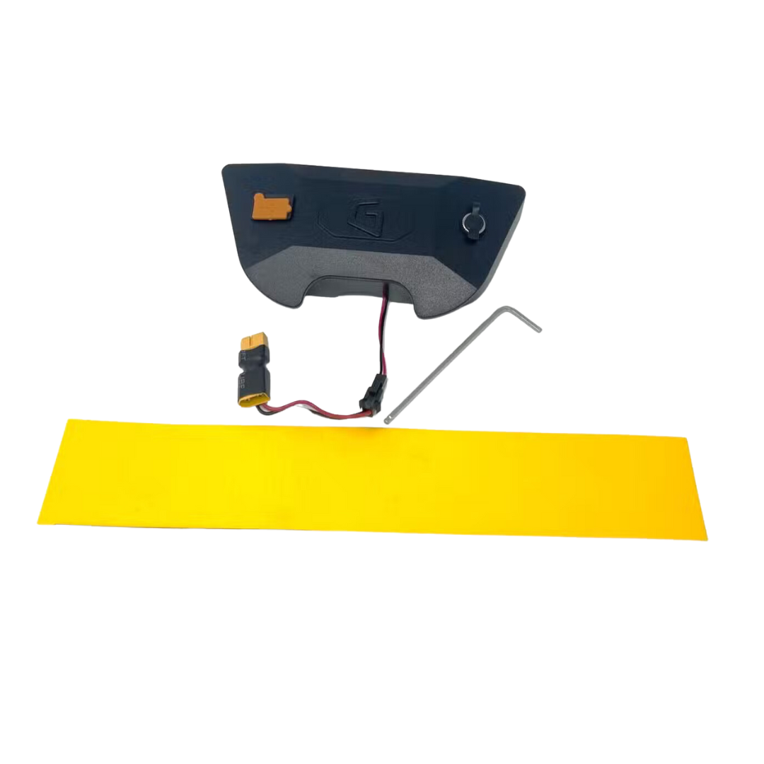 A black electronic component, possibly part of a Lithium-ion Battery for a mobility scooter, from Glion SNAPnGO Scooter Accessories is placed next to a long rectangular yellow strip and a small L-shaped metal tool on a plain white background.